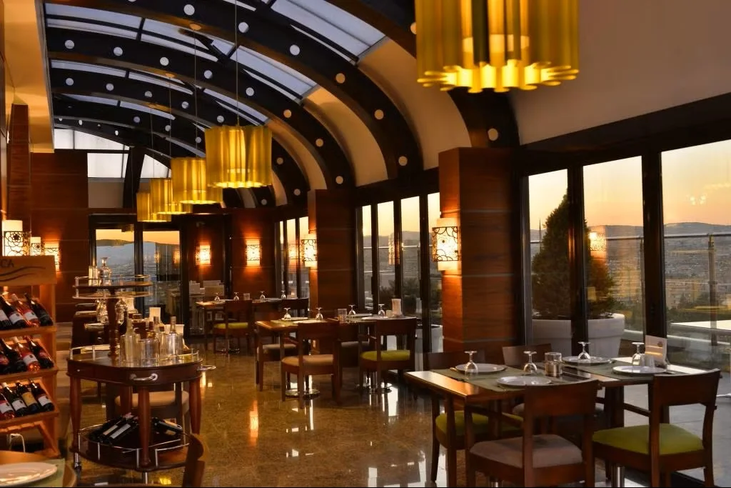Tuğcan Otel'in dış görünüşünü yansıtan geniş açı çekim, otelin Gaziantep'teki merkezi konumunu ve sunduğu konforlu konaklama imkanlarını vurgulayarak ziyaretçilere keyifli bir deneyim vaat ediyor.