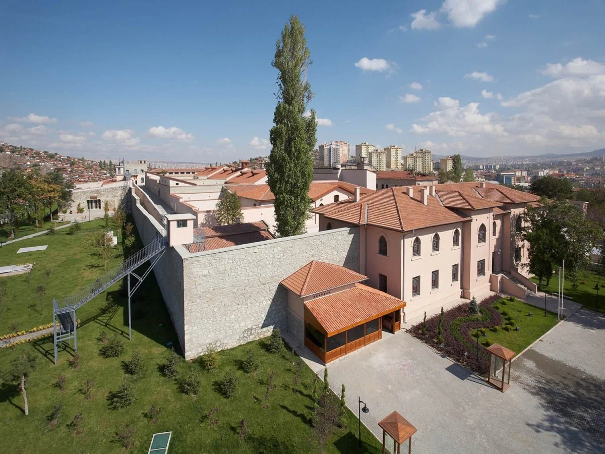 Ulucanlar Cezaevi Müzesi'nin taş duvarları ve ağır demir kapılarıyla çevrili, ziyaretçilere tarihin derinliklerini hissettiren daracık koridoru, geçmişin izlerini taşıyan loş ışıklı bir atmosferde eski bir hücrenin kapısını gözler önüne seriyor.