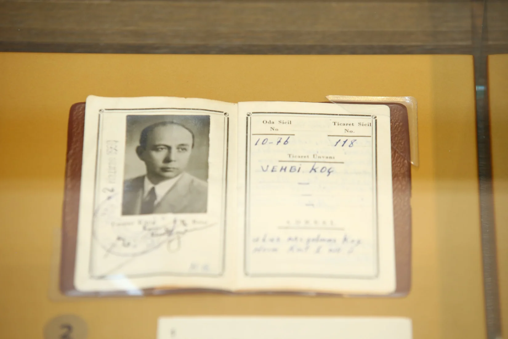 Türkiye'nin önemli sanayicilerinden Vehbi Koç'un, arşiv niteliğindeki bu siyah beyaz fotoğrafında, masasında takım elbiseli ve kravatlı olarak oturduğu, elinde bir kalem tutarak ciddi bir ifadeyle doğrudan kameraya baktığı ve önünde bazı evrakların da yer aldığı görülüyor; bu kare onun iş dünyasındaki uzun ve etkili sicilini gözler önüne seriyor.
