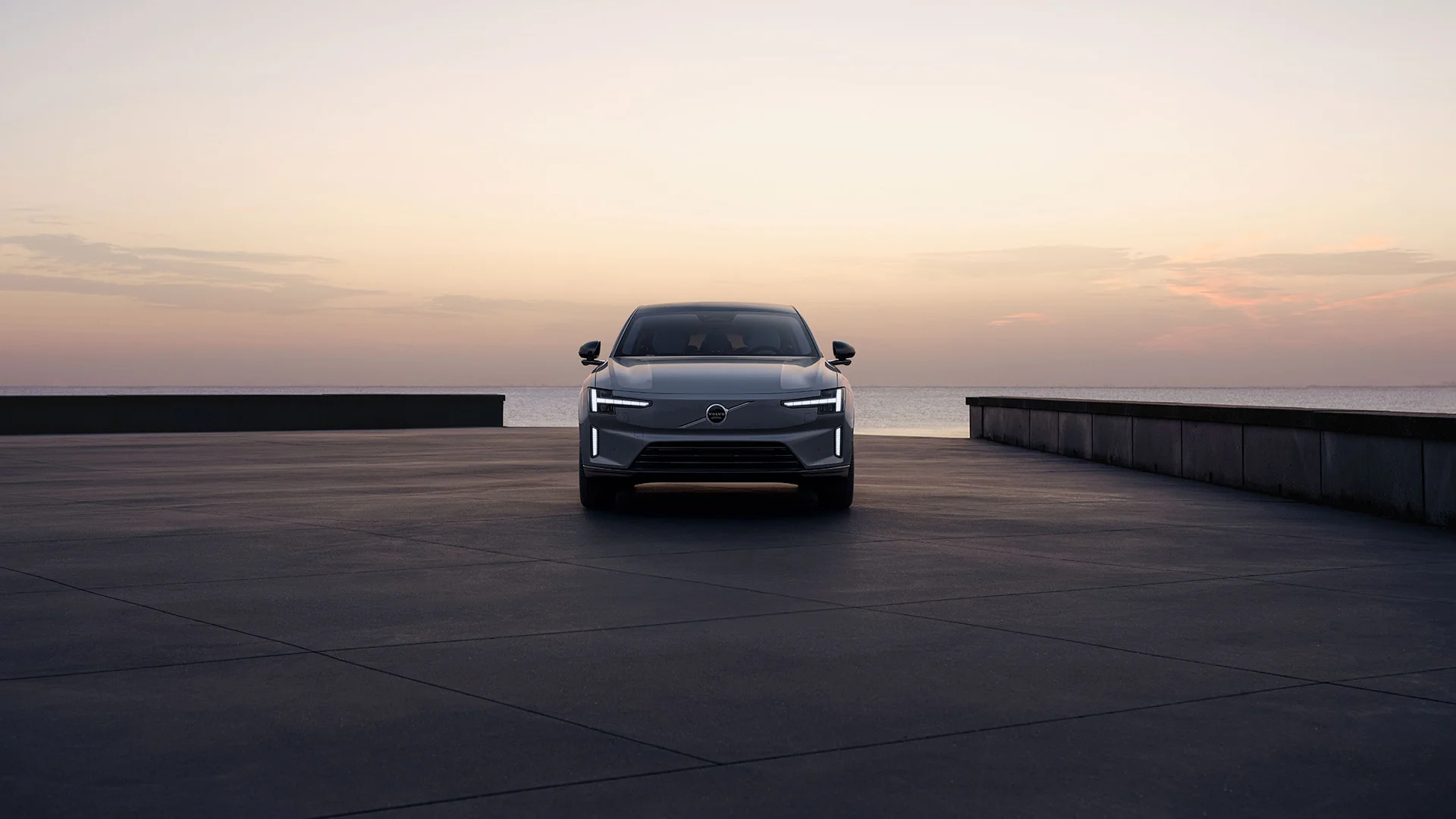 Volvo ES90 elektrikli sedanın modern iç mekanında, ortada konumlandırılmış büyük dikey dokunmatik ekranı, dijital gösterge paneli ve şık direksiyonuyla teknolojik bir sürüş deneyimi sunan minimalist tasarım detayları sergileniyor.